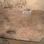 Fig. 5. This wide and thick cedar timber, found inside a cave at Mersa/Wadi Gawasis in 2007, remains to be fully excavated. Both ends have clearly been reworked. The left end of the upper face displays parts of two dovetail-shaped open mortises. A through mortise visible near the lower edge retains traces of a copper alloy "strap." Two round peg ends can be seen toward the upper edge.