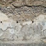 Fig. 8. House VI.13.13, Pompeii, right ala, detail of back wall with holes for shelves (the top row has been concealed by modern restoration).