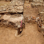 Fig. 12. View of the horos stone in relation to the east wall of Building X. View from the south.