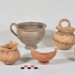 Fig. 4. Selection of ceramic vessels from Tomb 5 in the Blue Stone Structure; left to right: bichrome cup with stylized dolphins (P1505), matte-painted vertical ring-handled cup (P1504), Gray Minyan cup (P1503), undecorated kantharos (P1513), matte-painted vertical ring-handled cup (P1502), lustrous decorated askos (P1528).