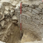 Fig. 5. Unfinished cold pool in Room 2, west side. The original low front wall (the top step) of the intended pool can be seen at lower left. After the earthquake, the apse wall was cut back vertically (immediately to the left of the pole), and a makeshift wall was constructed across the front of the pool (left, center; for its front side, see print fig. 9) (scale: 2 m).