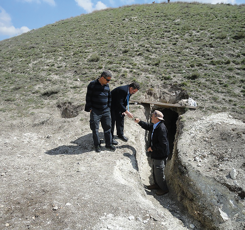 Entrance to the 2013 robber tunnel into the tumulus as found, with Vahap Kaya handing one of the Middle Phrygian sherds from the spoil heap to Gordion Museum guard İbrahim Bolat, with Mehmet Akalın of the Museum of Anatolian Civilizations in Ankara (Z. Utğu).