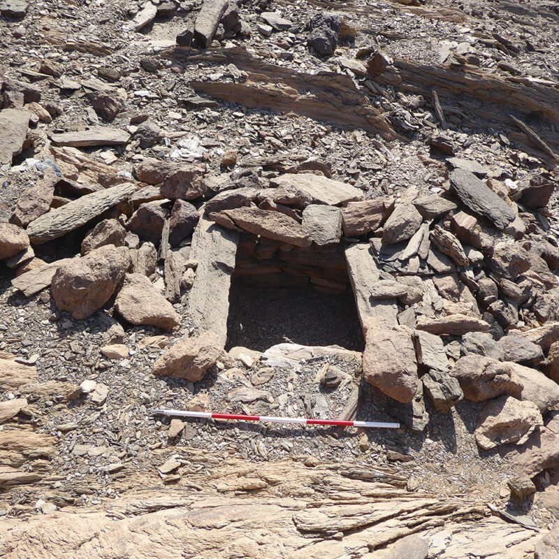 Type I tomb located in the Southeast Necropolis at Wadi Sikait (SKP-NEC-SE-T24). The damaged tumulus allows the rectangular funerary box to be visible; scale = 1 m.