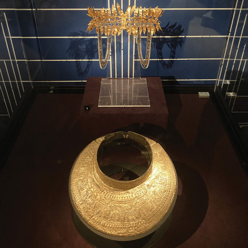View of the final case display in the exhibition: gold wreath and lunula (breastplate collar). Golden wreath with Nike figure and rosette appliqués: Iron Age (375–325 BCE), from burial assemblage at Zlatinitsa-Malomirovo, Bulgaria. Sofia, National Museum of History 50454–50455. Golden lunula, solid iron and covered and bossed silver plate and thin golden sheet: Iron Age (350–300 BCE), found at site Kosmatkite, Bulgaria. Sofia, National Museum of History 66069 (courtesy A. Gyucha).